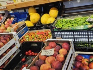 Pesche, meloni e verdure fresche in bancarella di mercato ortofrutta. Frutta di stagione e prodotti agricoli biologici disponibili per acquisto immediato.