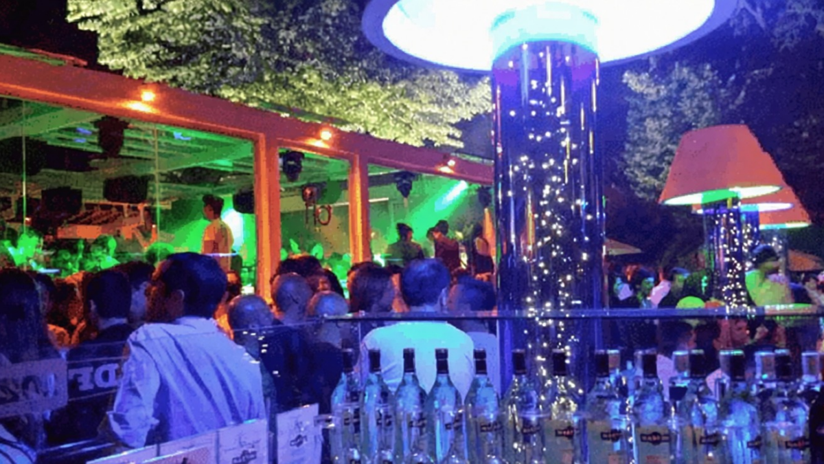 Gruppo di persone che si divertono in un club notturno con luci colorate e atmosfera vivace, ambiente moderno e alla moda, perfetto per serate di svago e socializzazione.