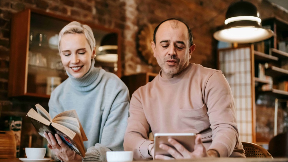 Aggiornare SEO: discussione tra giovani adulti che leggono e si confrontano in un bar alla moda con pareti in mattoni rossi, illuminazione calda e scaffali di libri in stile vintage.