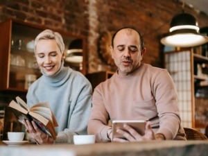 Aggiornare SEO: discussione tra giovani adulti che leggono e si confrontano in un bar alla moda con pareti in mattoni rossi, illuminazione calda e scaffali di libri in stile vintage.