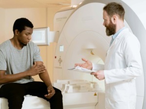 Imaging scans, consulente medico e paziente in ambulatorio. Qualità delle immagini sanitarie e diagnosi. Immagine di un medico e un giovane paziente durante una visita medica in clinica radiologica.