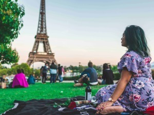 Vista della Torre Eiffel di Parigi al tramonto con persone che fanno un picnic nel parco, ambiente romantico e turistico, ideale per contenuti su viaggio, Francia e cultura europea.