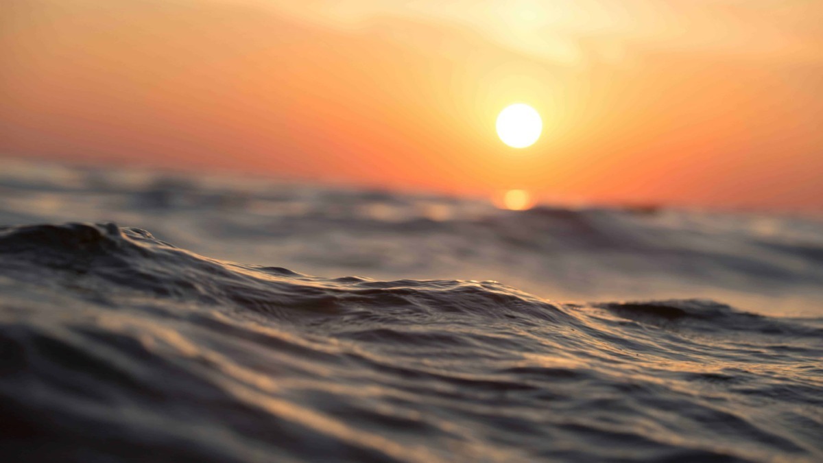 Onde del mare al tramonto, vista ravvicinata, atmosfera serena e colori caldi, scena naturale e rilassante.