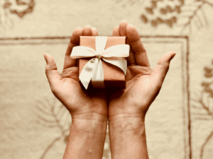 Piccolo regalo con fiocco in mano, idea di regalo speciale, presentazione di un dono per occasioni come compleanni o anniversari, simbolo di affetto e pensiero gentile.