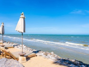 Parapioggia sulla spiaggia con ombrelloni e lettini in stile riposo estivo, mare blu e cielo sereno, ideale per relax, vacanze e gite sulla costa.