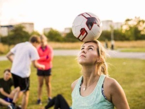 Balanace perfetta della donna mentre fa trick con il calcio sulla testa, allenamento sportivo, attività all'aperto, gioco di soccer, concentrazione e coordinazione.
