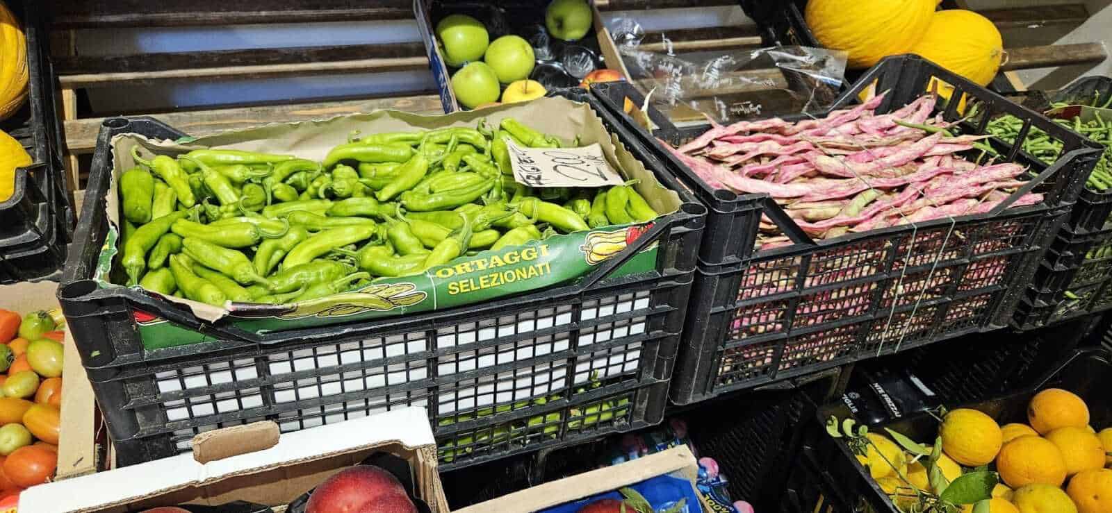 Frutta e verdura di agosto: Fresh green peppers in crates at a farmers market for healthy cooking ingredients, showcasing fresh produce selection.