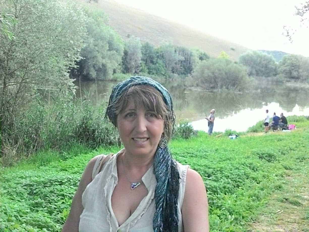 Vita all'aperto sul fiume, donna con sciarpa blu e camicia bianca, paesaggi naturali, incontri tra amici, relax nella natura, attività di pesca, ambiente tranquillo, scenari verdi e serene, escursione all'aperto, ritratto di donna felice.