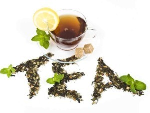 Tè alle erbe con limone e menta in tazza trasparente, con infusi di tè e zucchero di canna, decorato con foglie di menta fresca e teaposture di foglie e zuccheri, ideale per una bevanda rinfrescante.