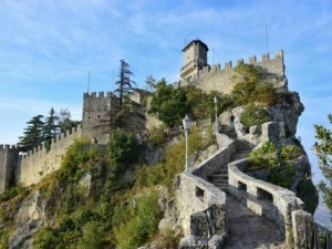 Castello medievale su scogliera con scale in pietra e vegetazione, panorama storico e turistico, destinazione da visitare in Italia, fortezza affascinante e panorami mozzafiato.