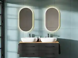 Lavabo duo con specchi ovali a illuminazione retro a parete in bagno moderno con mobile sospeso nero e pareti azzurro pastello.