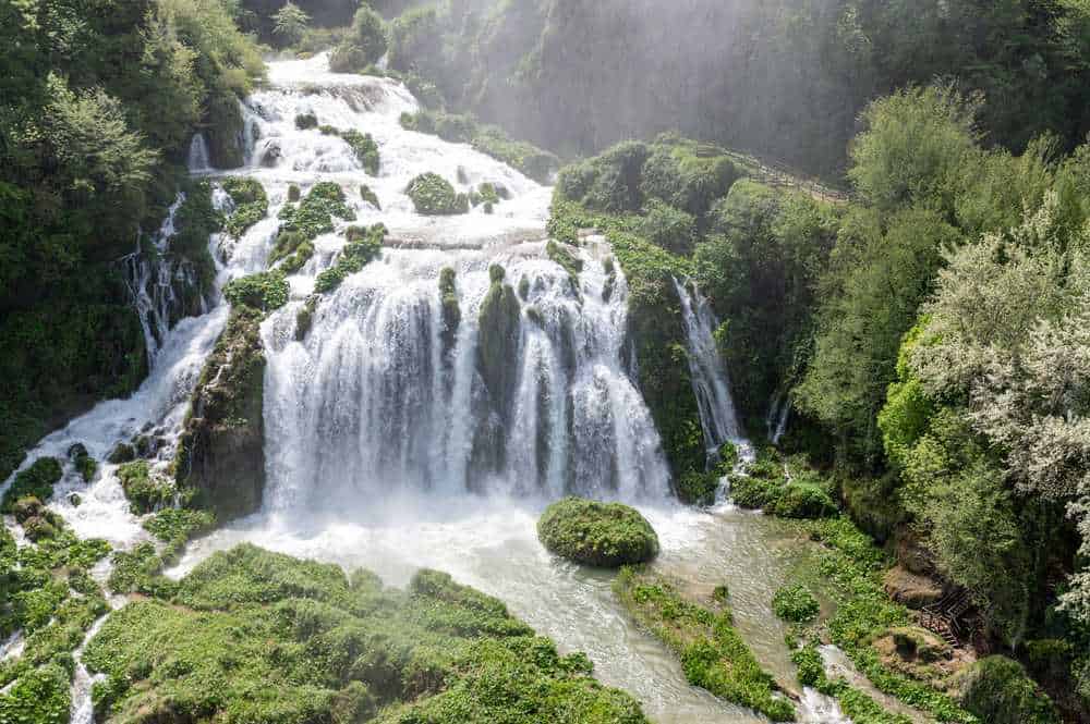 Cascata mozzafiato immersa in un paesaggio naturale di foresta verde e muschi, ideale per scoprire la bellezza della natura e itinerari di trekking in luoghi tranquilli e suggestivi.