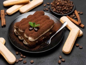 Tiramisù classico fatto in casa con mascarpone, cacao e Savoiardi, decorato con foglia di menta e chicchi di caffè. Dolce italiano amato e ricco di sapore, perfetto per ogni occasione.