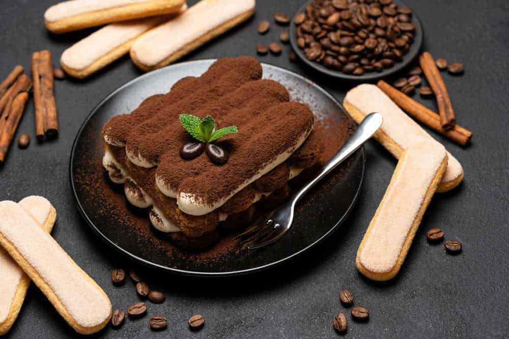Tiramisù classico fatto in casa con mascarpone, cacao e Savoiardi, decorato con foglia di menta e chicchi di caffè. Dolce italiano amato e ricco di sapore, perfetto per ogni occasione.