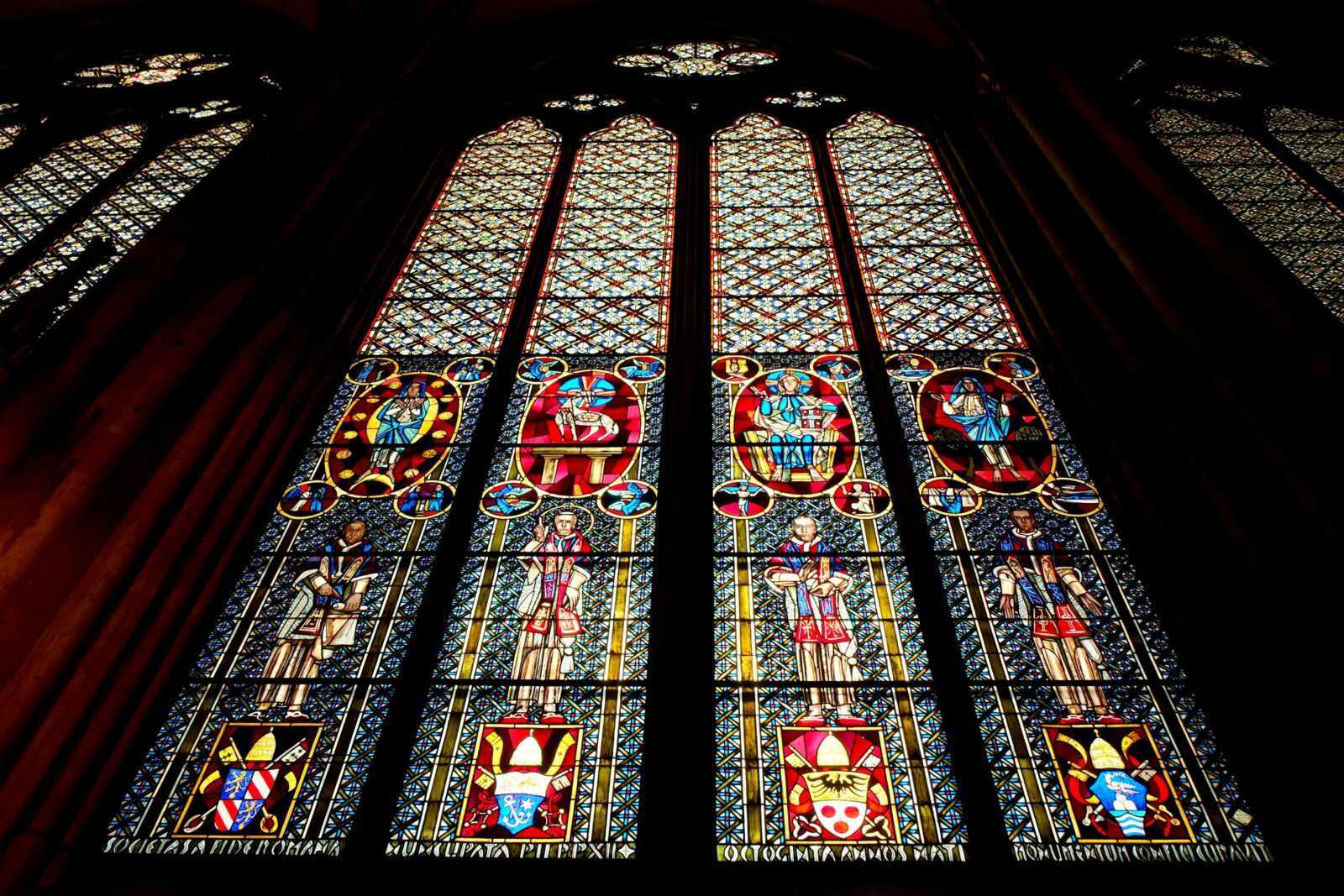Cos'è il gotico, arte gotica dal classico al moderno 6 Colorato vetro artistico con figure storiche e simboli religiosi, originale decorazione di una grande finestra in una chiesa gotica, creata con tecnica di vetrata colorata.
