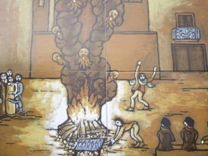 Fiamme che avvolgono un albero con figure umane e animali, mentre persone assistono e interagiscono, rappresentando una scena simbolica nella street art italiana.