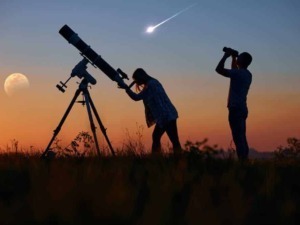 Telescopio astronomico sul prato al tramonto con due persone che osservano il cielo, meteore e fase lunare, esplorazione dello spazio, astronomia amatoriale, osservazione delle stelle.