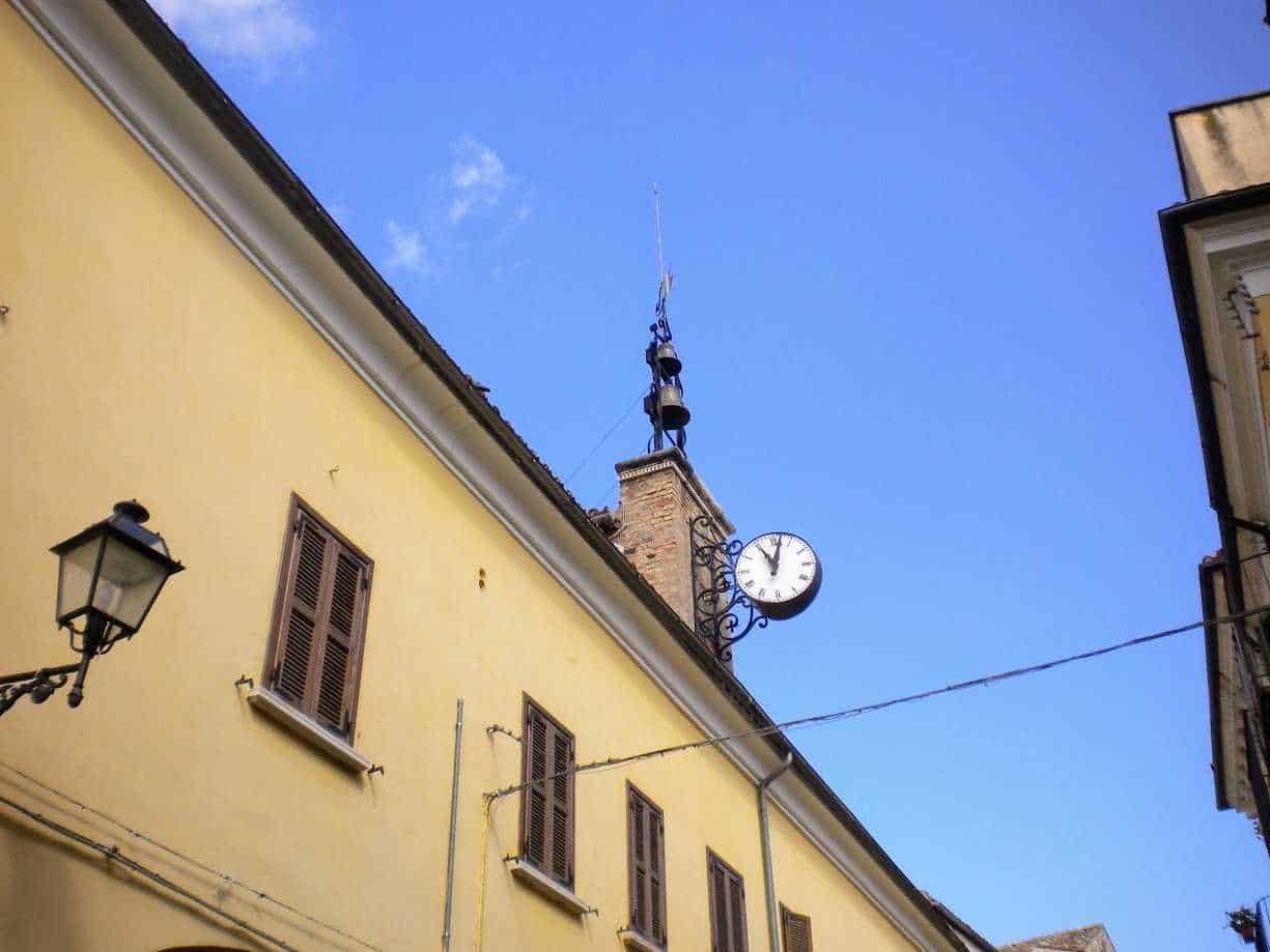 Pannello orologio su edificio storico nel centro di una città italiana, architettura antica, cielo azzurro, atmosfera urbana, dettagli classici, luogo di interesse culturale, appunti sul blog.
