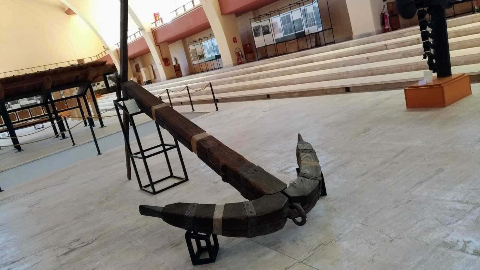 Banco in legno e ferro in un museo storico, ambiente interno con scala e mostre espositive.