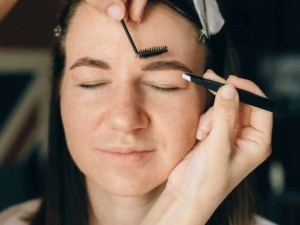 Estetista che applica extension ciglia su una donna con occhi chiusi, procedimento di lash extension, bellezza naturale, cura del viso, estetica professionale.