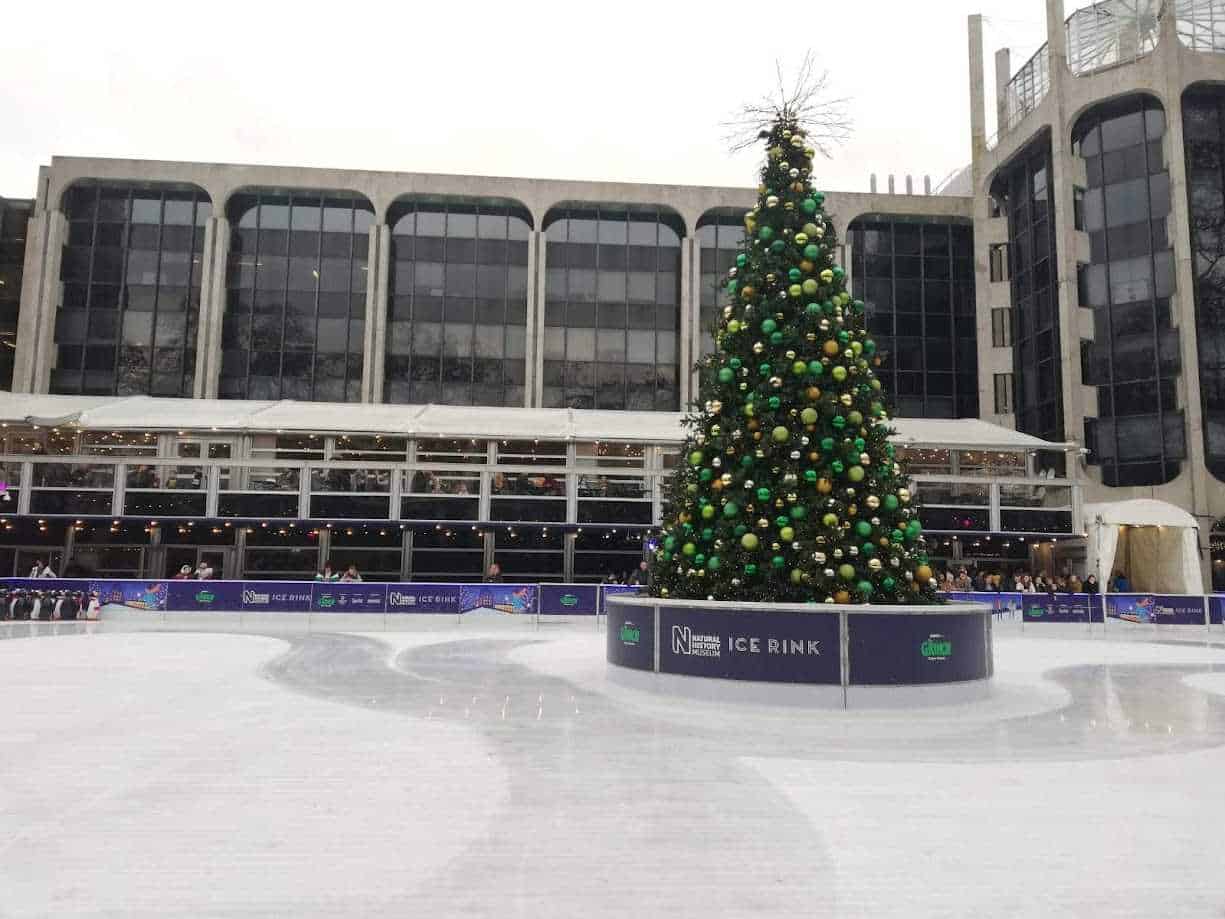 Altre testo_alt: Albero di Natale decorato con palline verdi e oro in una pista di pattinaggio sul ghiaccio all'aperto a Londra durante il periodo delle feste di Capodanno.
