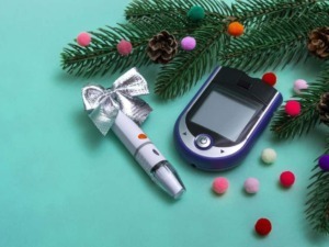 Apparecchi per la diagnosi del diabete: glucometro, lancette, kit di misurazione su sfondo natalizio con pigne e decorazioni colorate.