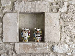 Vasi decorativi colorati a forma di teste di personaggi mitologici o fantasy in una nicchia in stile rustico, decorativi per interni con ceramica dipinta a mano.