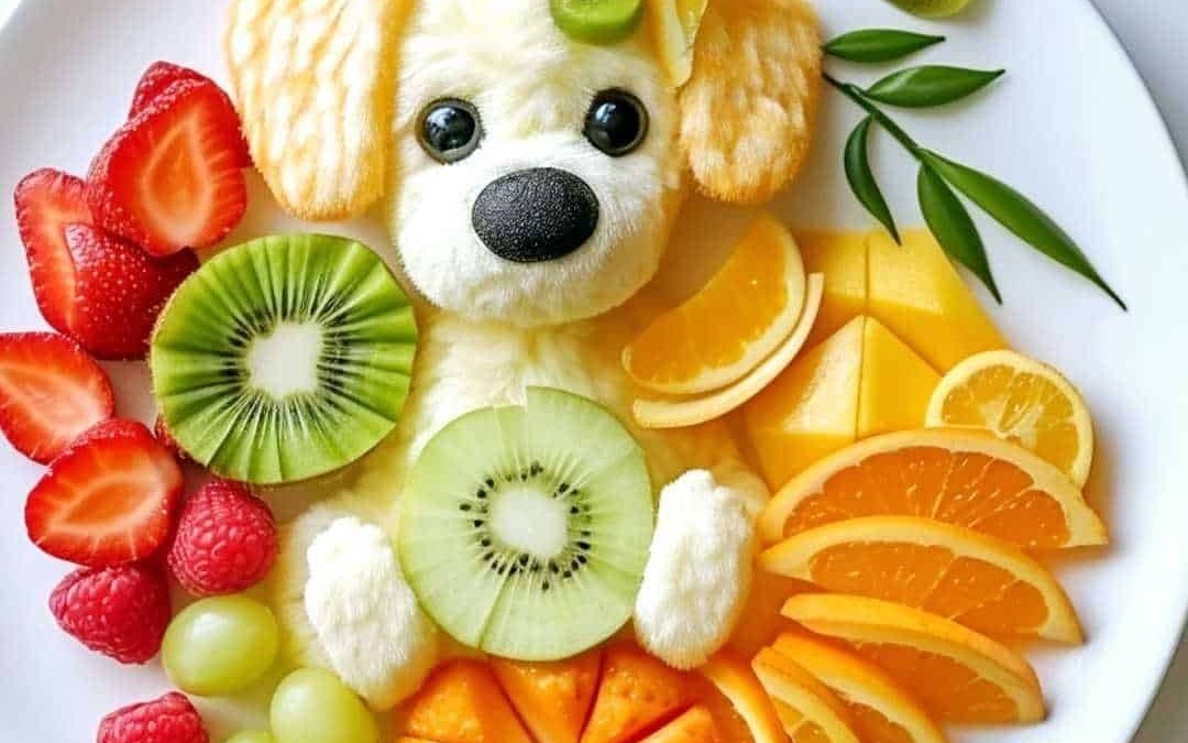 Colorato piatto di frutta con decorazione a forma di cane, con frutta fresca come kiwi, fragole, uva, arance e mandarini, e un mignolo di dolcezza.