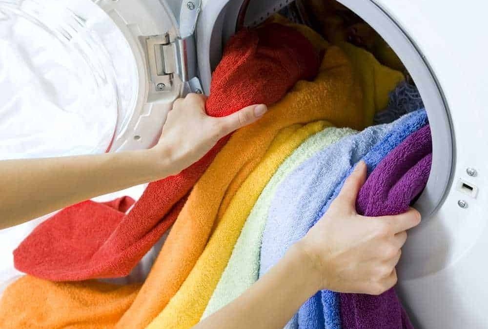 Lavatrice con asciugamani colorati in lavaggio, cura dei tessuti, biancheria colorata, lavaggio a casa, pulizia e cura degli asciugamani di cotone.