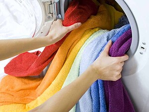Lavatrice con asciugamani colorati in lavaggio, cura dei tessuti, biancheria colorata, lavaggio a casa, pulizia e cura degli asciugamani di cotone.