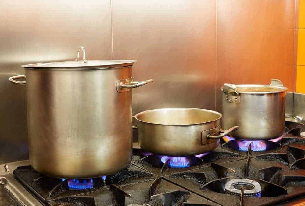 Pentole da cucina industriali in acciaio su fornelli a gas in cucina commerciale.