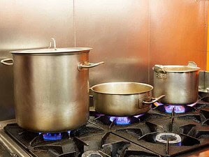 Pentole da cucina industriali in acciaio su fornelli a gas in cucina commerciale.