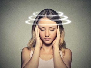 Donna che tiene le mani alle orecchie con luci di effetti digitali a spirale sopra la testa, rappresenta mal di testa o stress mentale.