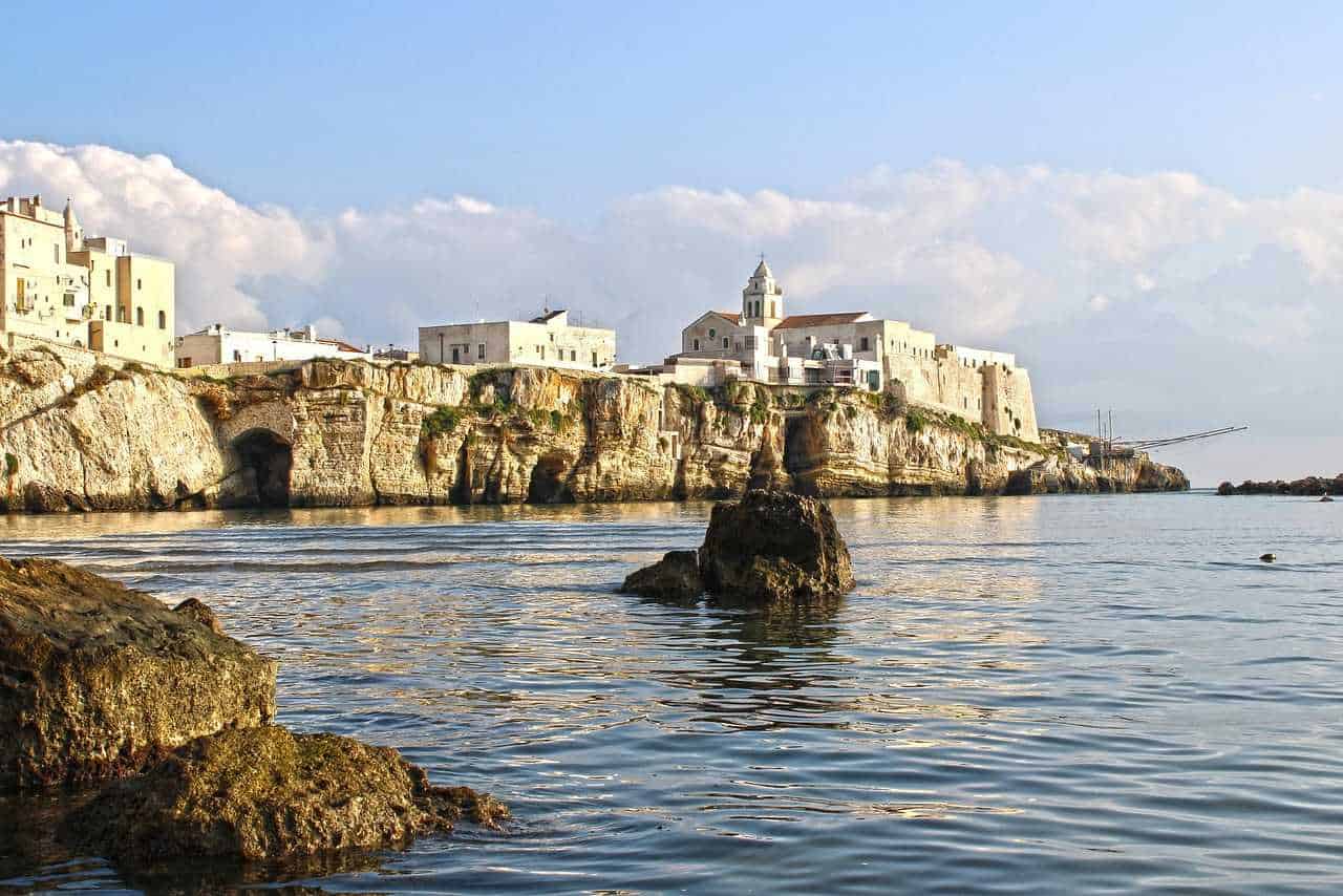 È il momento giusto per prenotare le tue vacanze estive 2 Fronte del mare con case bianche e scogli a Polignano a Mare, Puglia, Italia. Spiaggia naturale e vista panoramica sulla costa mediterranea. Paesaggio marino e architettura tradizionale pugliese.