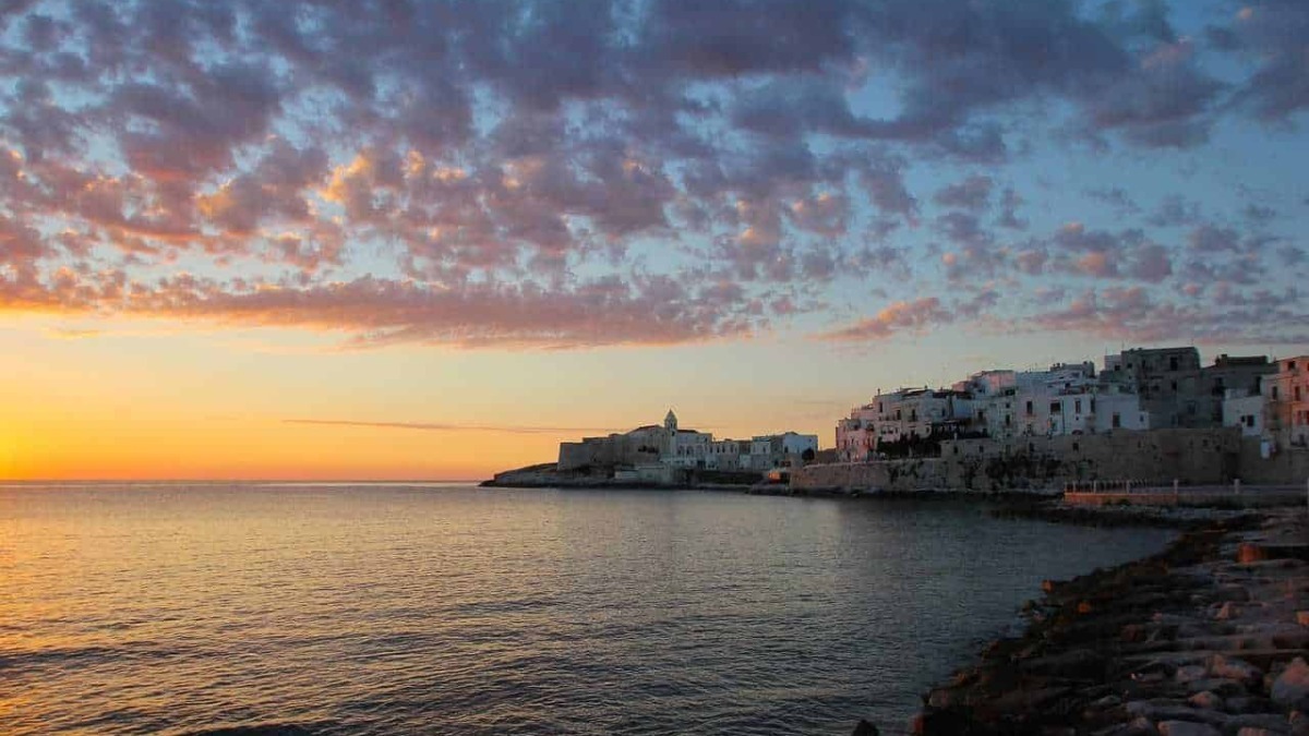 Tramonto sulla costa di Apulia con cielo colorato e paesaggio marittimo.