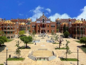 Castello in stile modernista, edificio storico affascinante con dettagli architettonici elaborati, situato in un parco verde con alberi e sentieri, sotto un cielo azzurro raggiante.