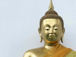 Buddha dorato con abiti tradizionali, statua sacra e simbolo di spiritualità e pace, su sfondo bianco, rappresentando serene pratiche di meditazione e filosofia buddista.