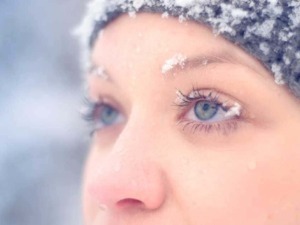 Neve sulla fronte, viso della donna, ritratto di una ragazza con cappello di lana in inverno, dettagli dei lineamenti e della pelle pure, atmosfera fredda e serena.