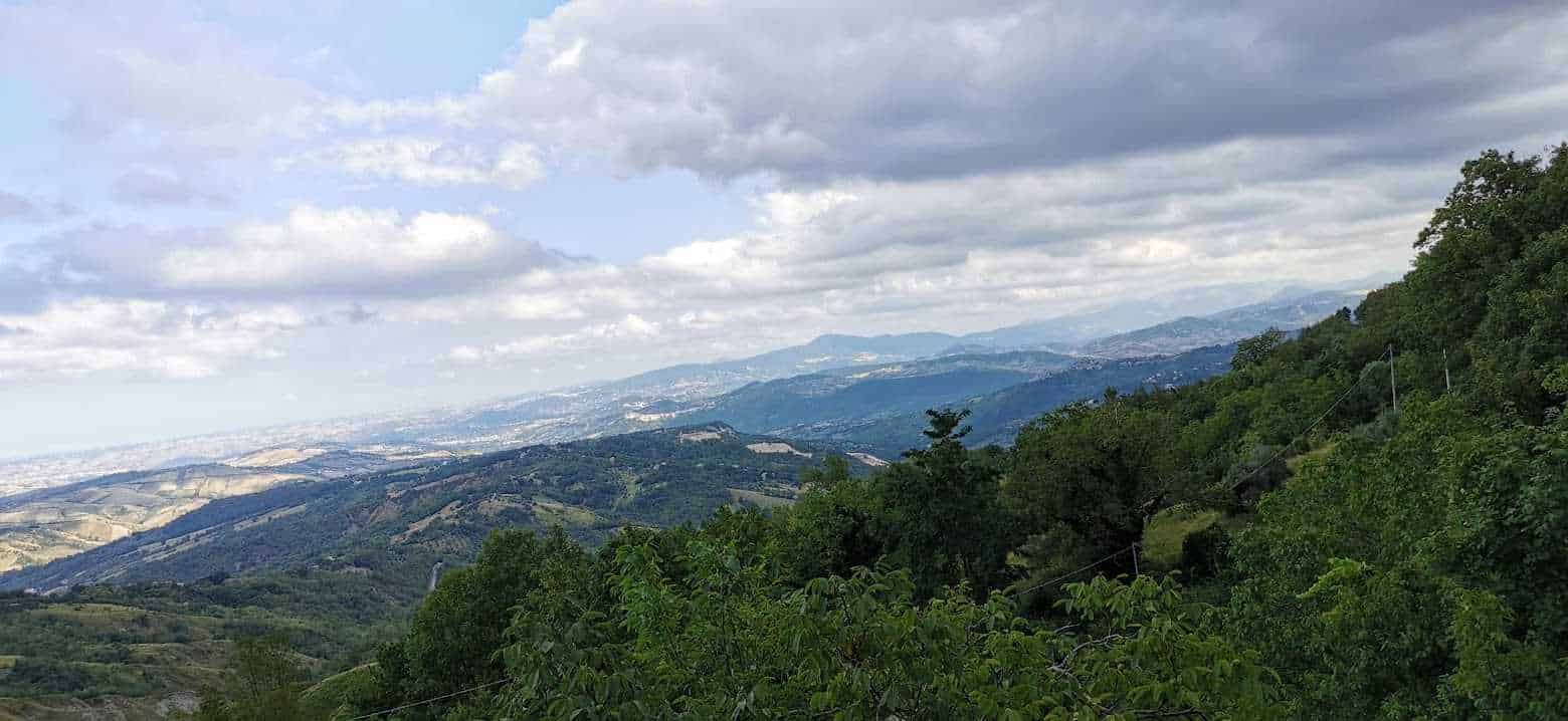Paesaggio collinare verde con montagne lontane e cielo nuvoloso, vista panoramica delle colline toscane, ideale per articoli di viaggio e natura su Appunti Sul Blog.