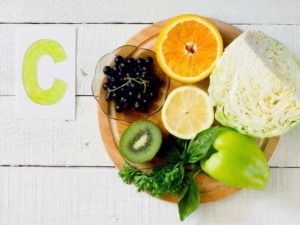 Fruits e verdure fresche come arancia, limone, kiwi, uva, lattuga e peperone su un tagliere di legno, ideali per una dieta sana ricca di vitamina C e antiossidanti.