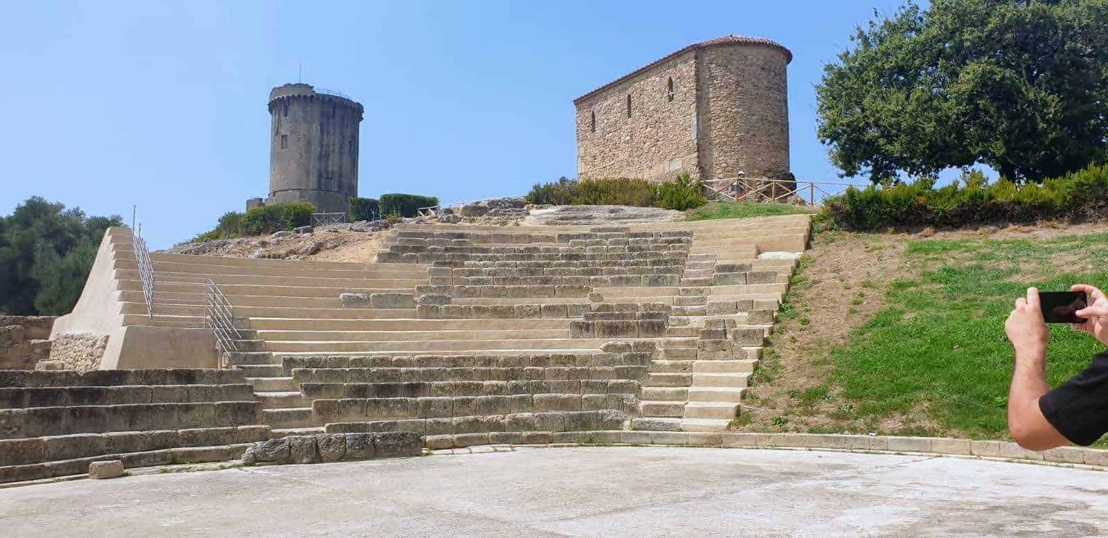 Velia e paestum: Antica struttura con scalinate in pietra e torri medievali su un prato verde, sito archeologico storico in Italia.