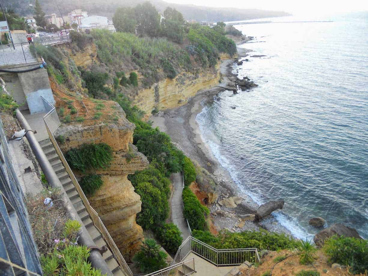 Scogliera con sentiero panoramico e vista sul mare, paradiso naturale sull'Adriatico con piante verdi e roccia arenaria.