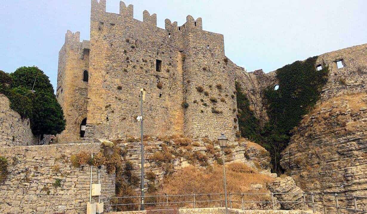 Majestic castello medievale su una roccia, con mura in pietra e merlature, immerso in un paesaggio storico, perfetto esempio di architettura antica e cultura locale.