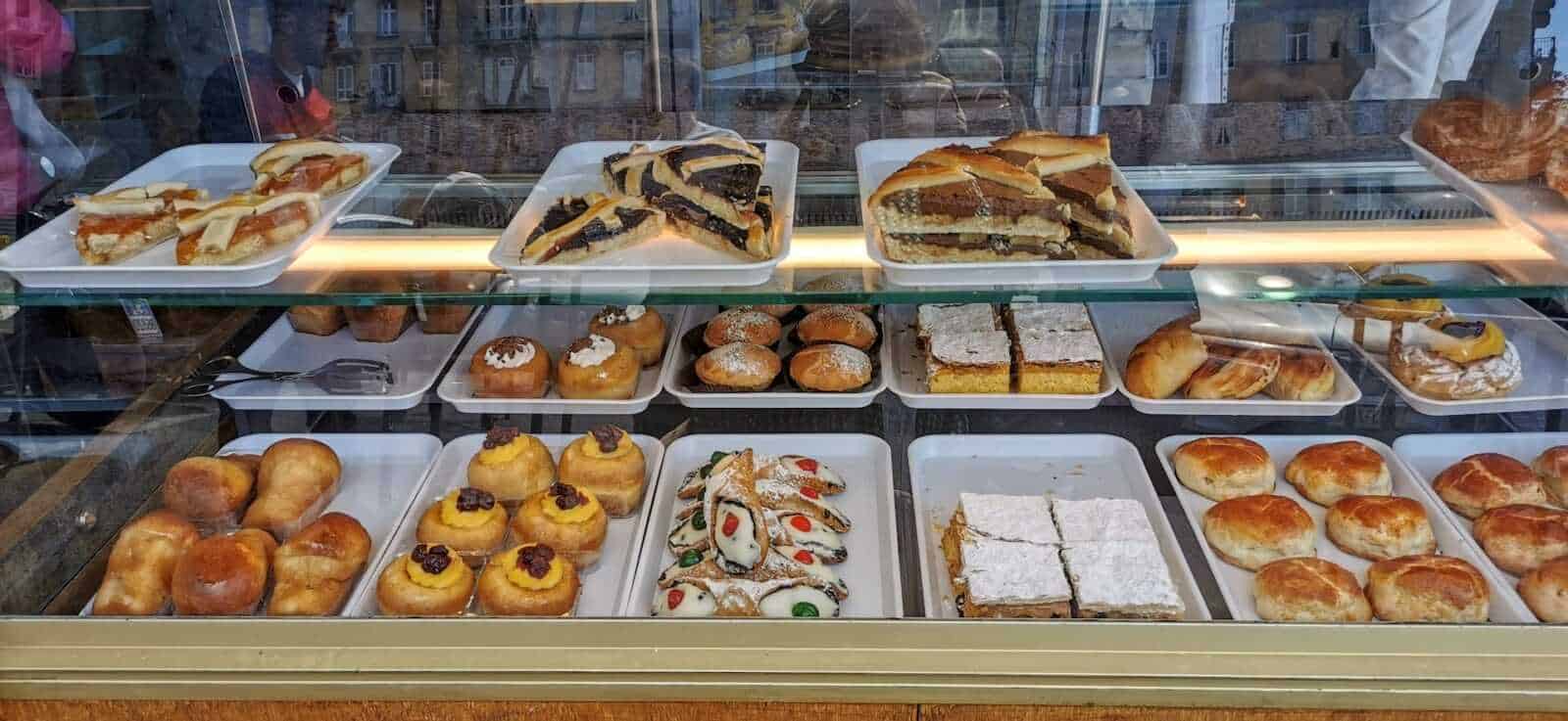 Dolci e pasticceria in vetrina di una panetteria italiana, tra croissant, torte e dessert tradizionali.
