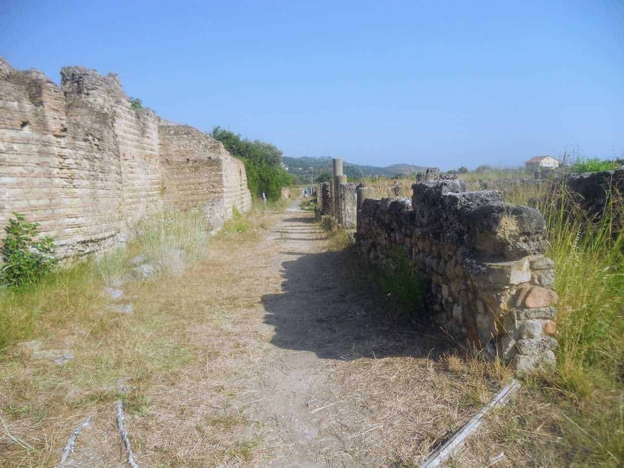 Antica strada romana con resti di mura in pietra, storia e archeologia, paesaggio rurale, turismo culturale, sentieri storici in Italia.