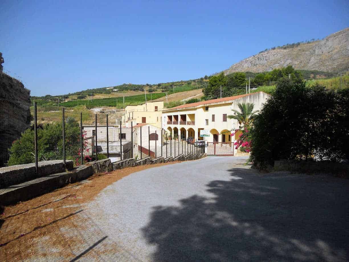 Magazzino storico in stile mediterraneo con archi e balconi, immerso in una pittoresca campagna collinare, circondato da natura e vigneti, ideale per blog di viaggi e lifestyle.