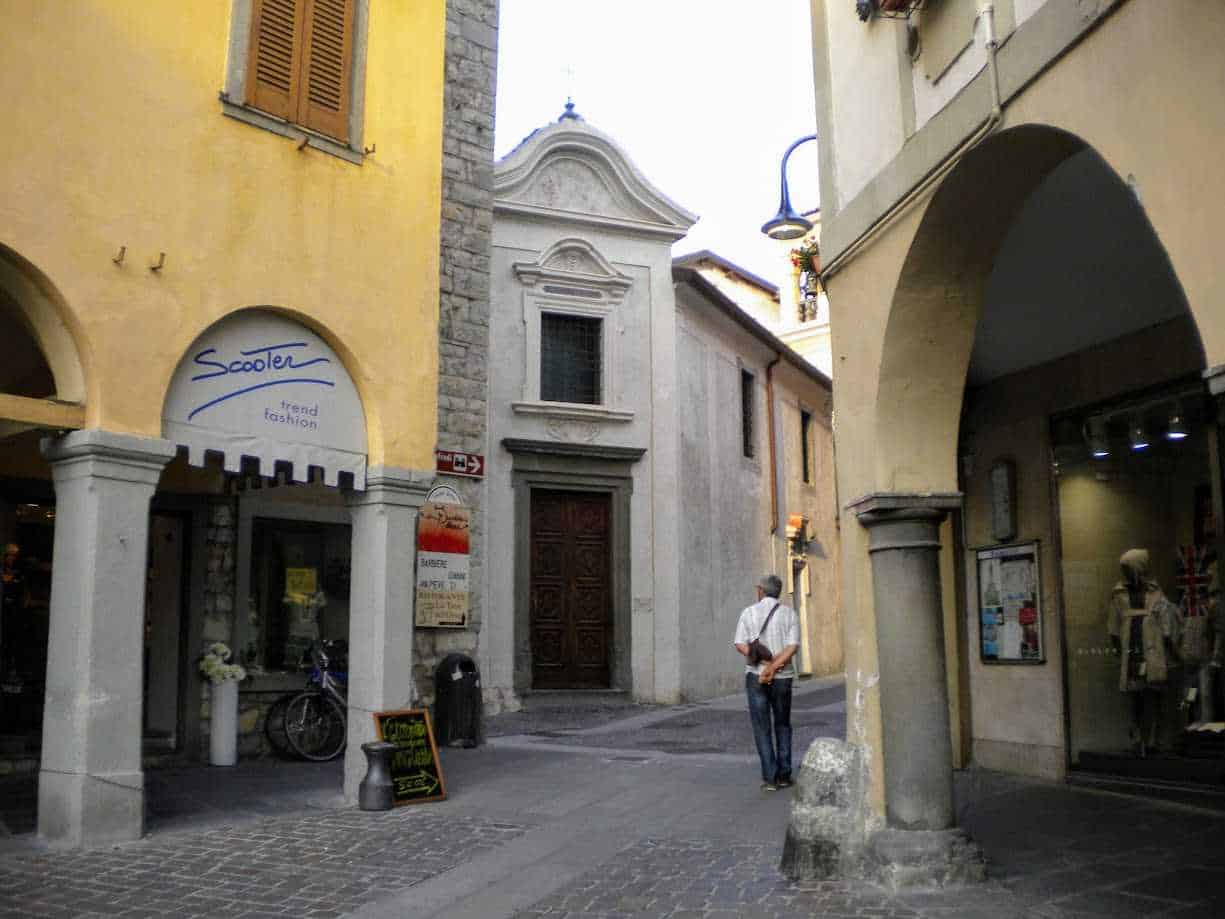 Cosa Vedere a Iseo città sul Lago di Iseo: centro storico, castello e lungolago 5 Antico vicolo nel centro storico di Iseo, case colorate e negozi con luci calde, atmosfera tipica italiana, e strada pedonale con edifici in stile veneto.