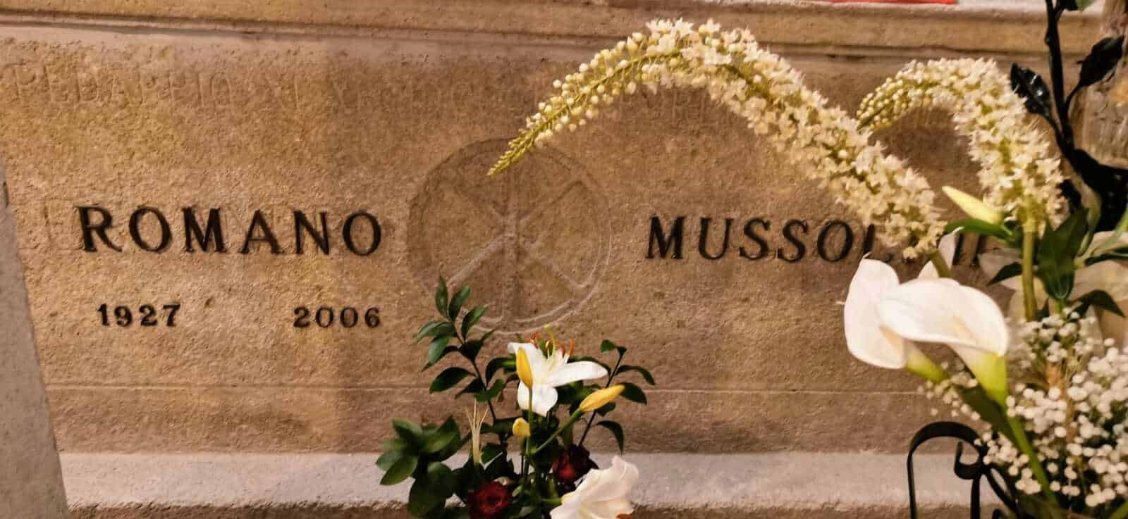 Cripta di Mussolini a Predappio: guida al Cimitero 5 Tomba di Romano Mussolini con decorazioni floreali e fotografia commemorativa.