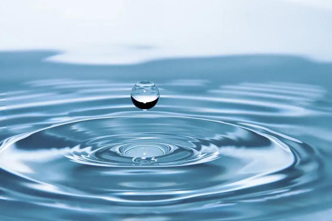 Goccia d'acqua che cade e crea cerchi concentrici sull'acqua, simbolo di fluidità e precisione nel potere dell'acqua naturale, ideale per contenuti sul blog come natura, scienza e benessere.