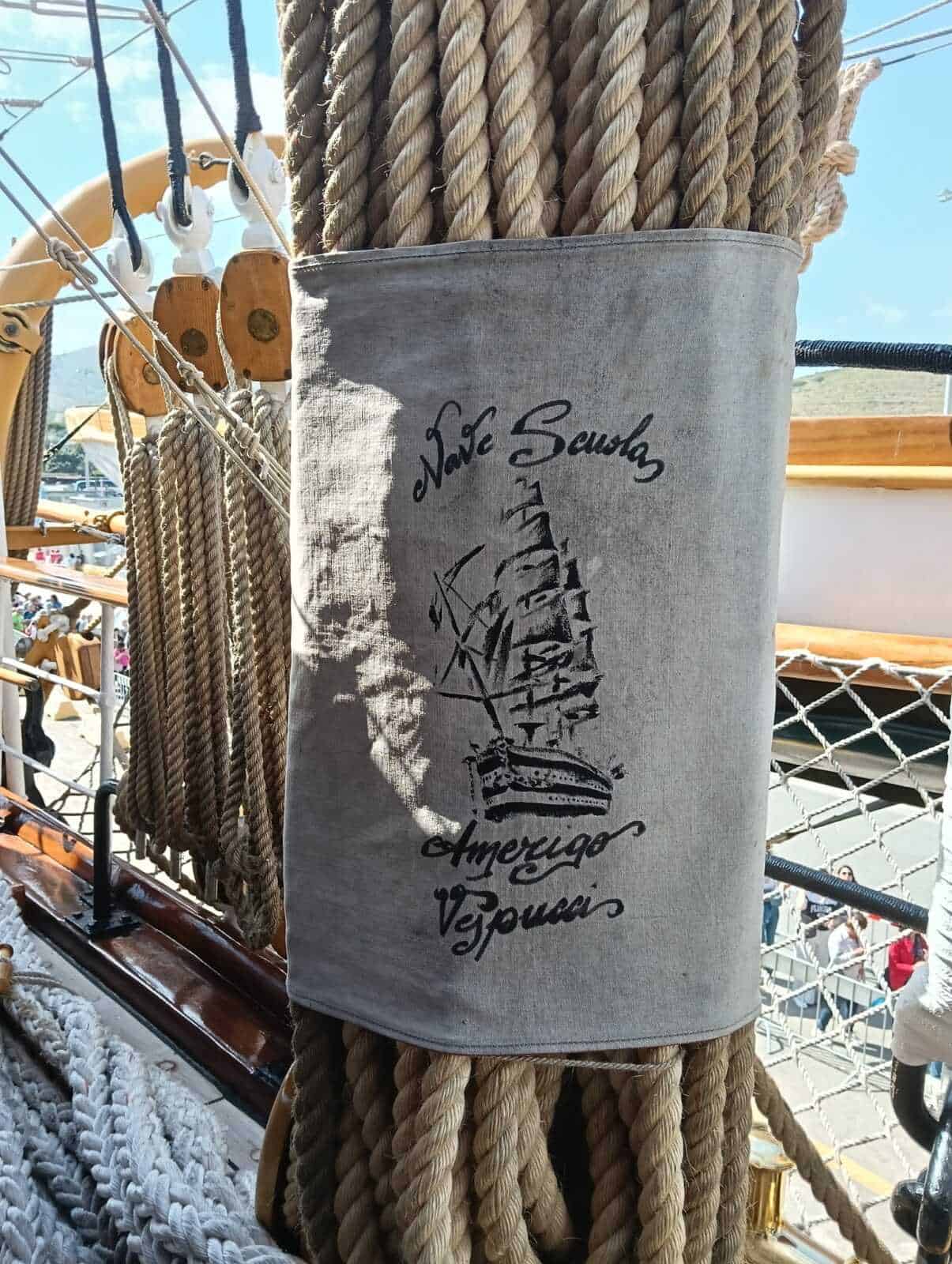Amerigo Vespucci a Napoli 2025: cosa sapere 13 Tovaglia in tessuto con stampa di un veliero e scritte "Save Seashells, Amo poco, Vesuvio", decorata con corde marinerie, in un contesto marittimo o nautico all'aperto.